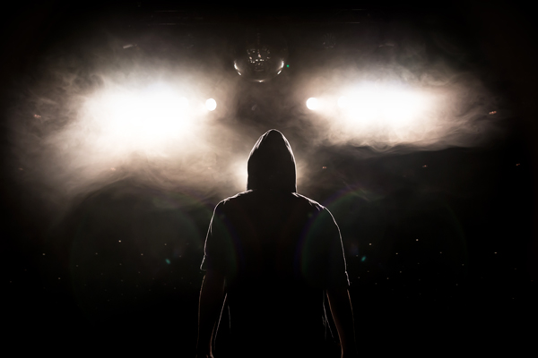 Mensch mit Kapuze im Gegenlicht einer Bühne © andessa/AdobeStock