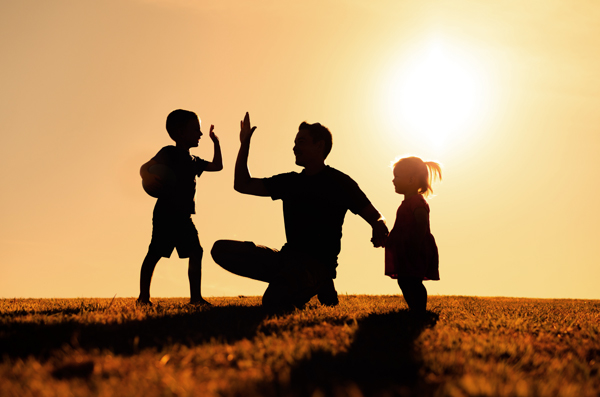 Vater mit zwei Kindern auf Wiese im Gegenlicht © kieferpix/AdobeStock